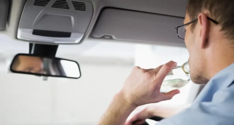 Un conducteur consommant de l'alcool au volant, illustrant les risques liés à l'alcoolémie et ses conséquences sur la sécurité routière et les assurances