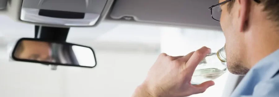 Un conducteur consommant de l'alcool au volant, illustrant les risques liés à l'alcoolémie et ses conséquences sur la sécurité routière et les assurances